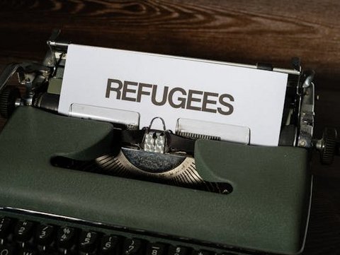 Schreibmaschine mit einem Blatt. Auf dem Blatt steht Refugees.